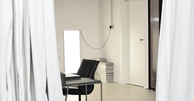 Studio Organization - Interior of spacious loft studio with meeting table and chairs surrounded by hanging white curtains